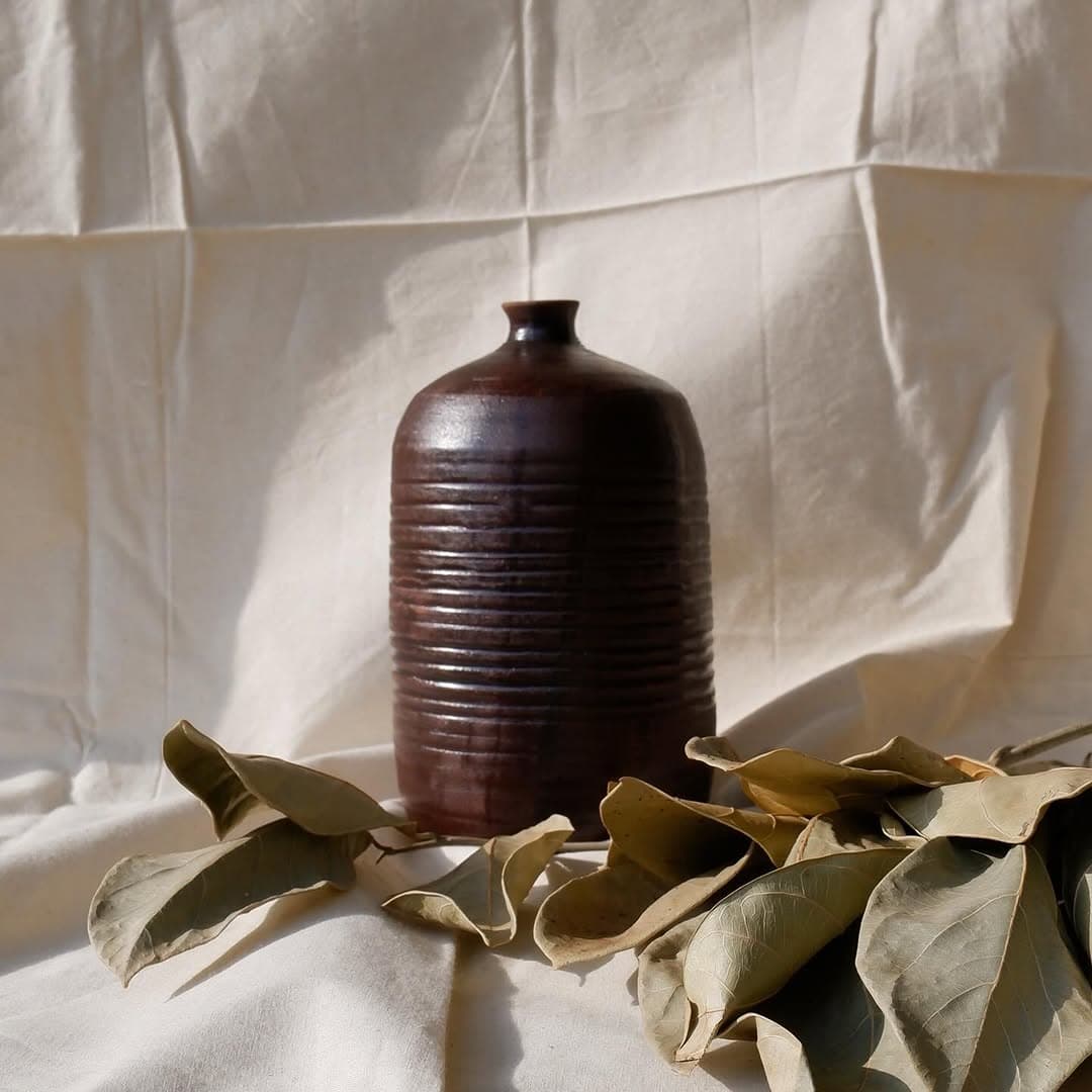 Dark handmade Studio Sira vase styled with dried leaves